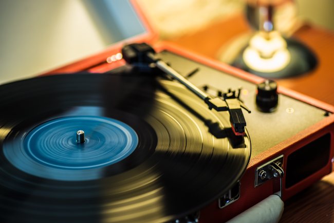 Image of a record player with warm hues and light shining down on it while it's spinning.
