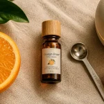 Huile essentielle orange douce sur lin beige, orange fraîche, bouchon bois, cuillère doseuse